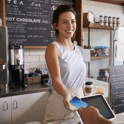 Customer at coffee shop pays smiling waitress with card